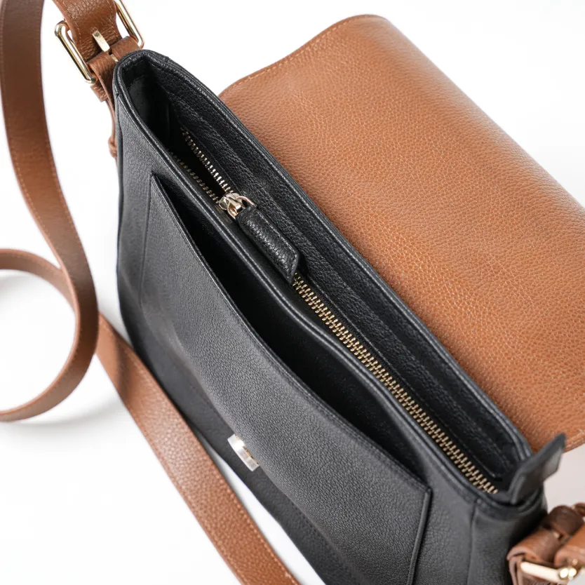 A black and brown genuine leather handbag with a zipper and flap closure, displayed against a neutral background.