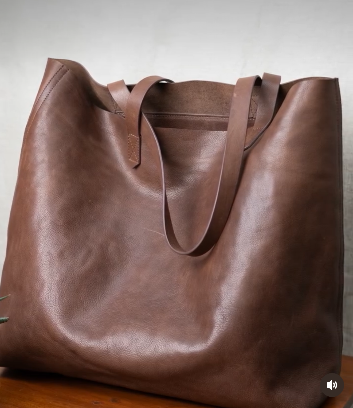 Brown leather tote bag on a wooden surface with a neutral background