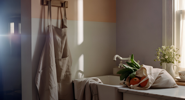 Beige Belgian linen apron, linen-cotton kitchen towel, and cotton slub shopping bag by Soulesthetic in a minimal natural kitchen setting.