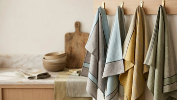 A well-organized kitchen with various linen towels displayed on hooks, adding a pop of color to the space. 