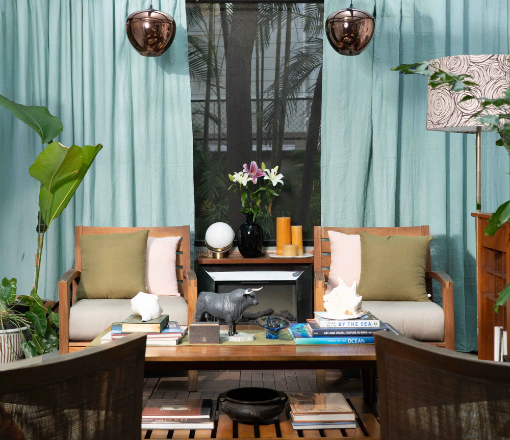 Living room with wooden chairs, a coffee table, and decorative items against a blue curtain.