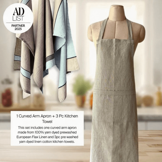 Curved arm apron and kitchen towels on a mannequin with a blurred kitchen background.