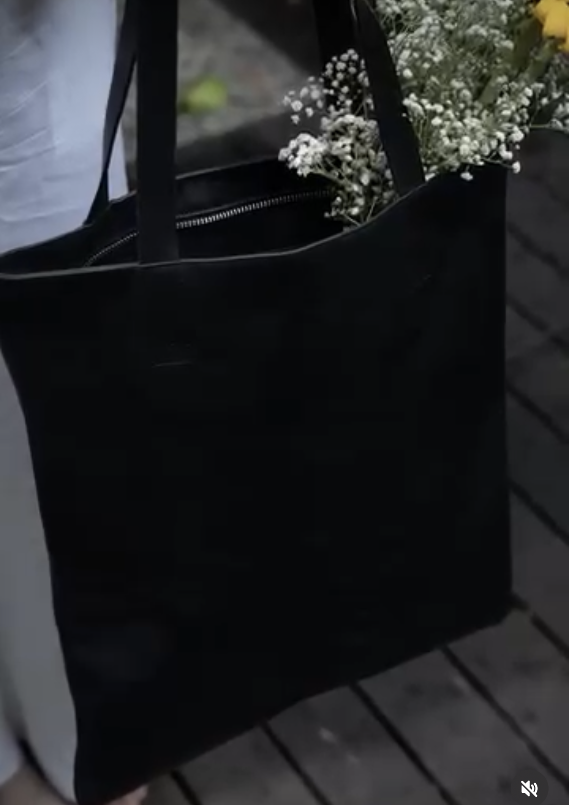 Black leather tote bag with flowers on a wooden surface