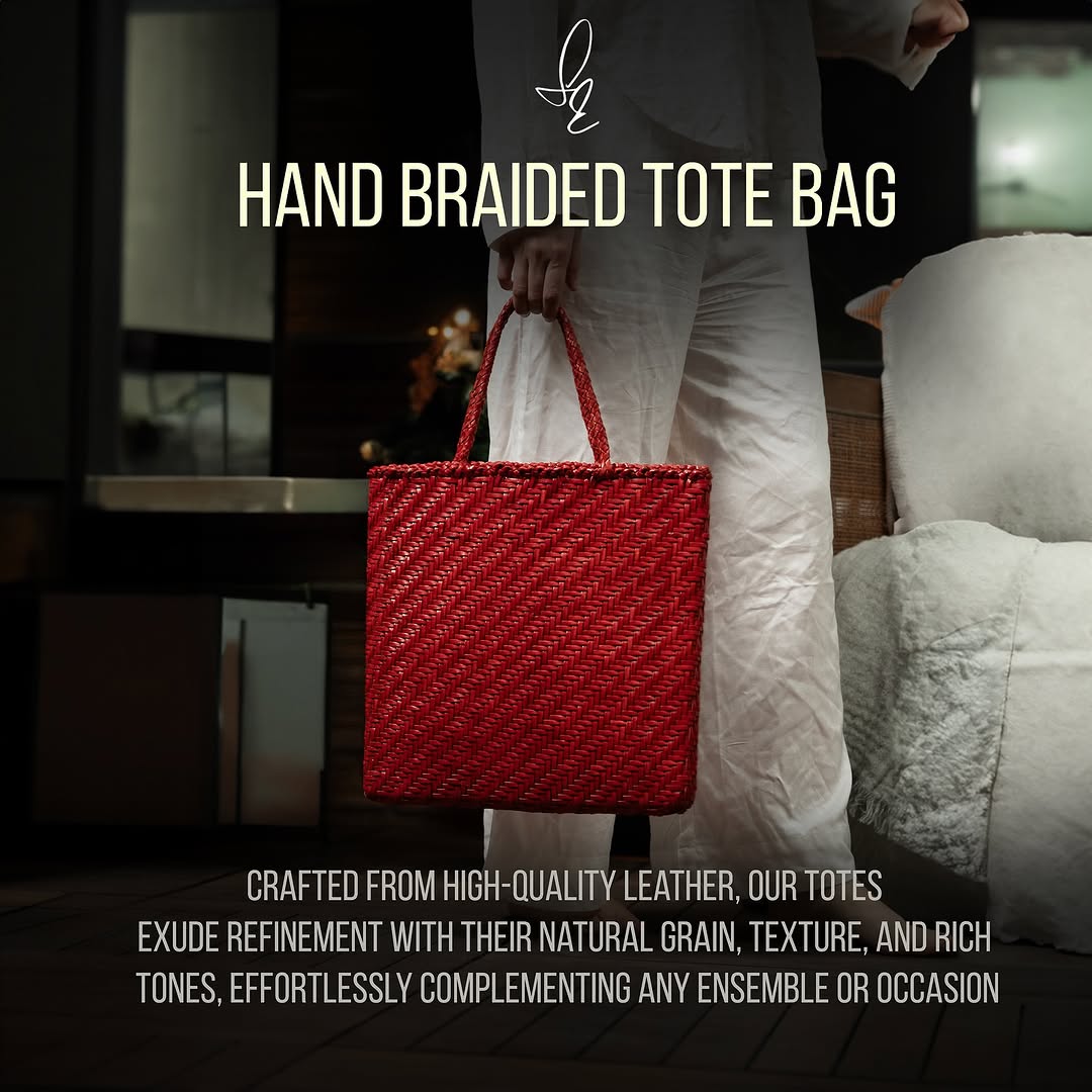Red hand braided tote bag held by a person in a blurred indoor setting