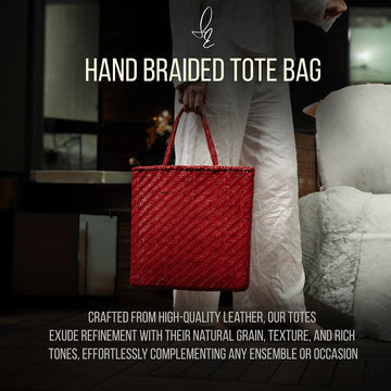 Red hand braided tote bag held by a person in a blurred indoor setting