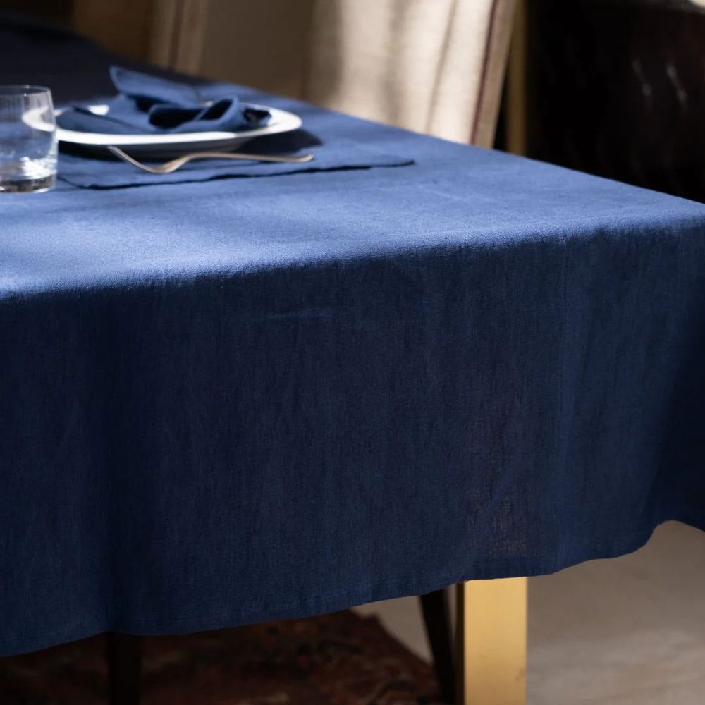 Navy blue tablecloth on a table with a glass and plate.