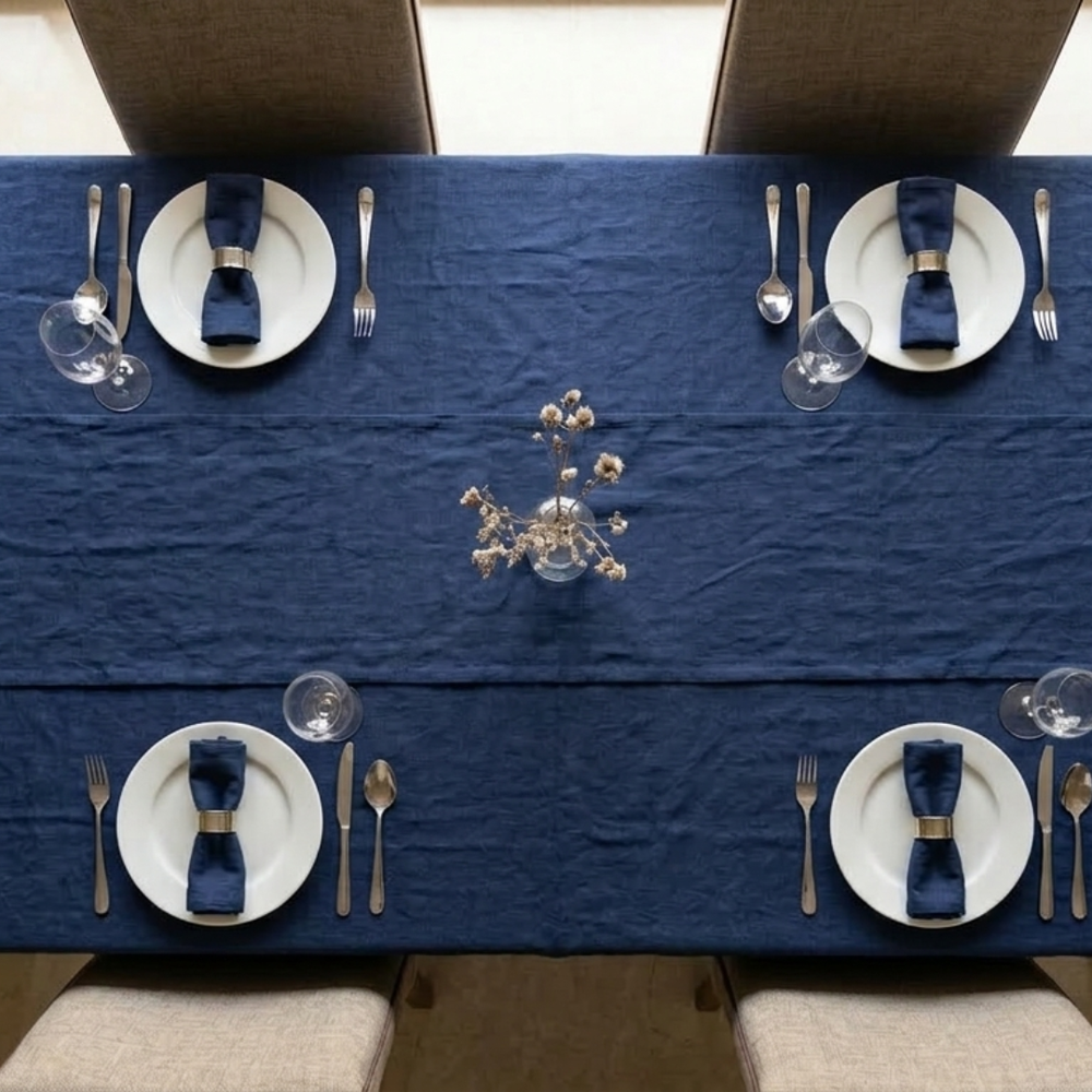 Dining table set with blue tablecloth, white plates, silverware, and centerpieces.