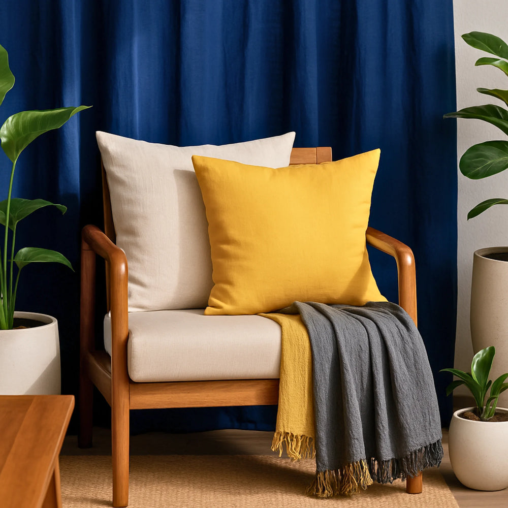 Wooden armchair with yellow pillow and gray blanket against a blue curtain