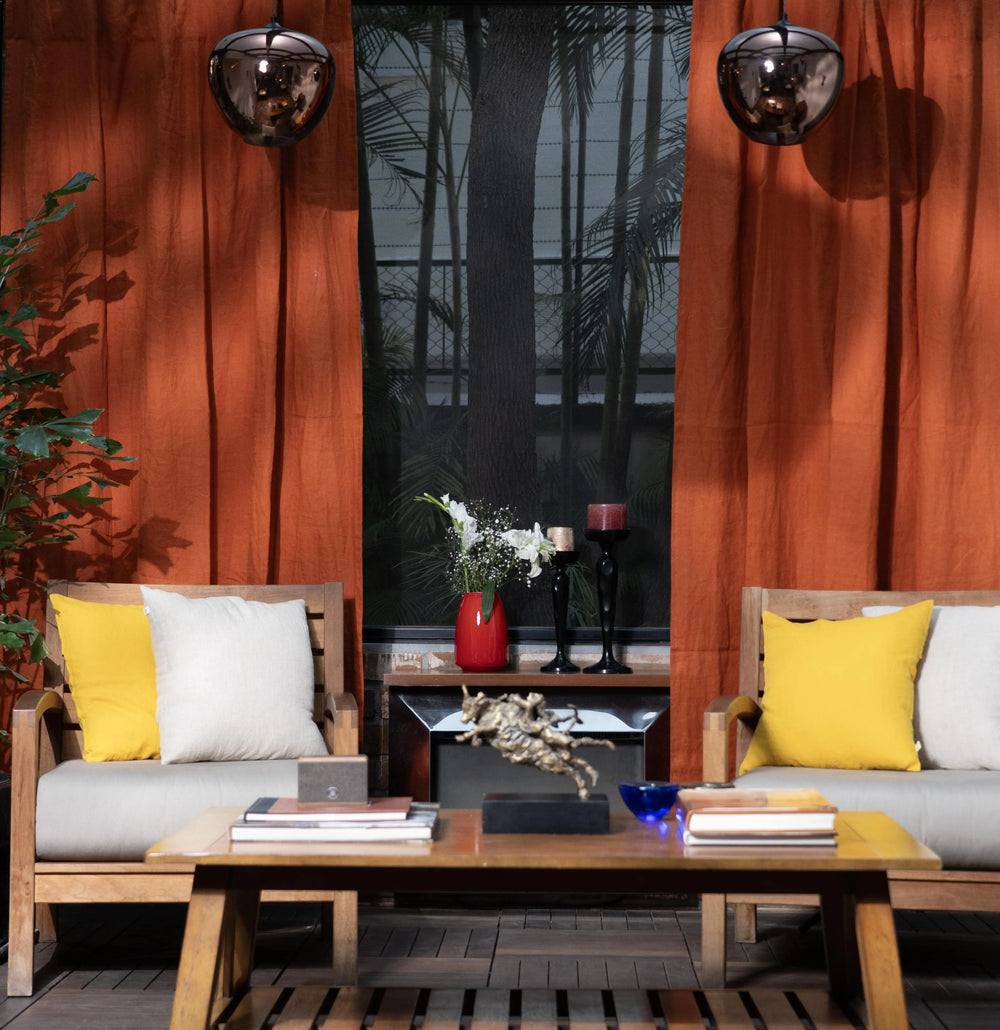 Modern outdoor seating area with wooden furniture, yellow and white cushions, and decorative items.