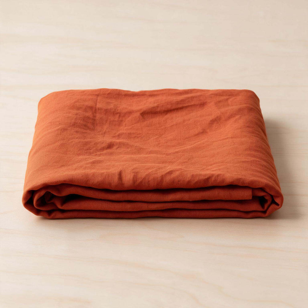 Rust Orange linen flat sheet set neatly folded with two pillowcases on a cream background, showcasing the rich terracotta stonewashed linen and complete set contents