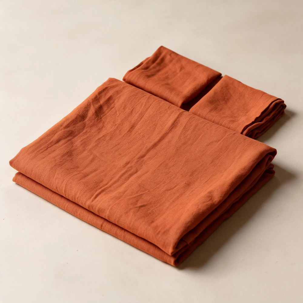 Rust Orange linen flat sheet set neatly folded with two pillowcases on a neutral background, showing stonewashed terracotta linen texture