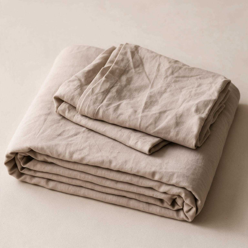 Taupe linen flat sheet and pillowcase neatly stacked and folded on a neutral background, showcasing the warm greige stonewashed linen texture