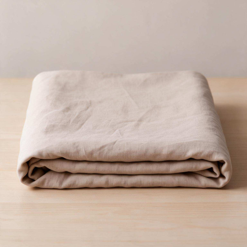 Taupe linen flat sheet neatly folded with a pillowcase stacked on top on a neutral background, showcasing the warm greige stonewashed linen and complete set contents
