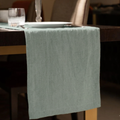 Green tablecloth draped over a wooden chair with a blurred background