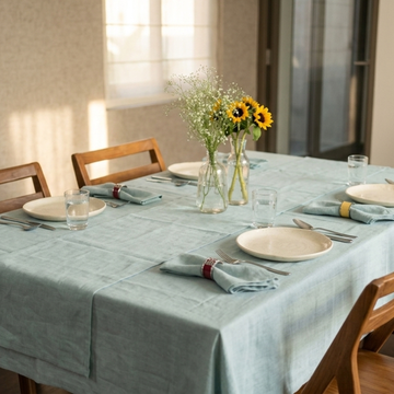 Dining table set with plates, glasses, and napkins, featuring a vase of sunflowers.