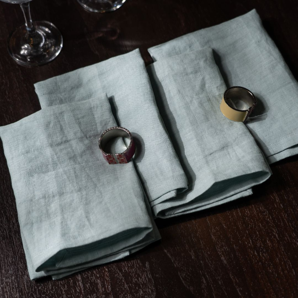 Light gray napkins on a dark wooden table with decorative rings.