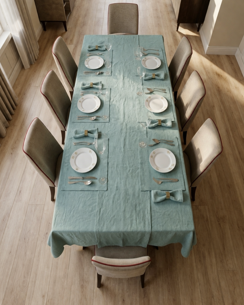 Dining table set with green tablecloth, plates, and chairs in a room.