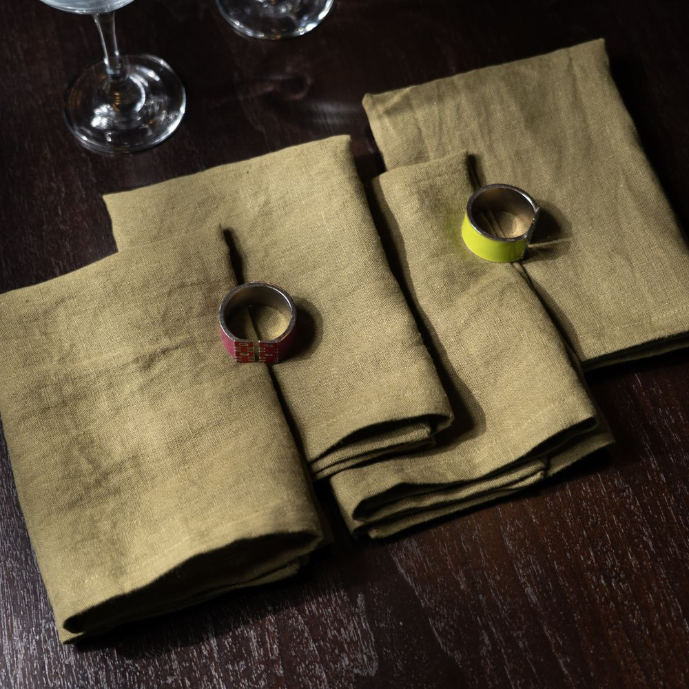 Folded green napkins on a dark wooden table with small decorative items.