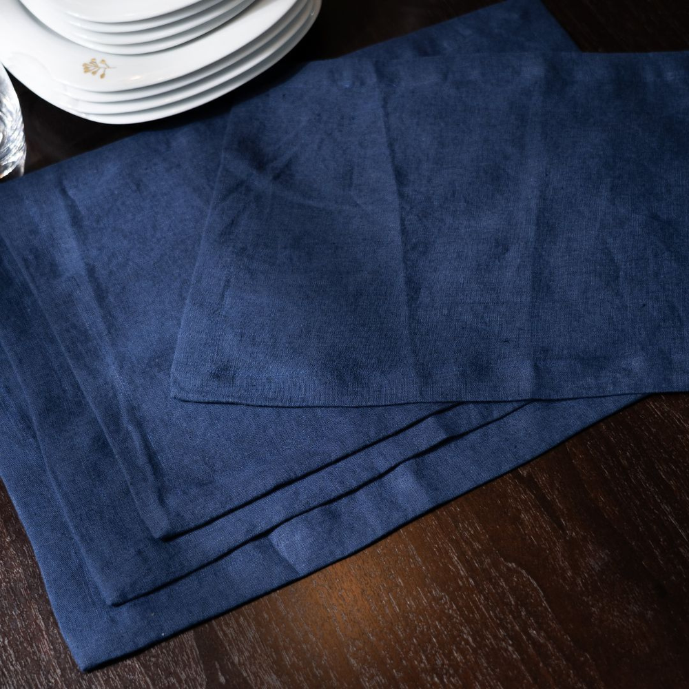 Blue placemats on a wooden table with white plates in the background
