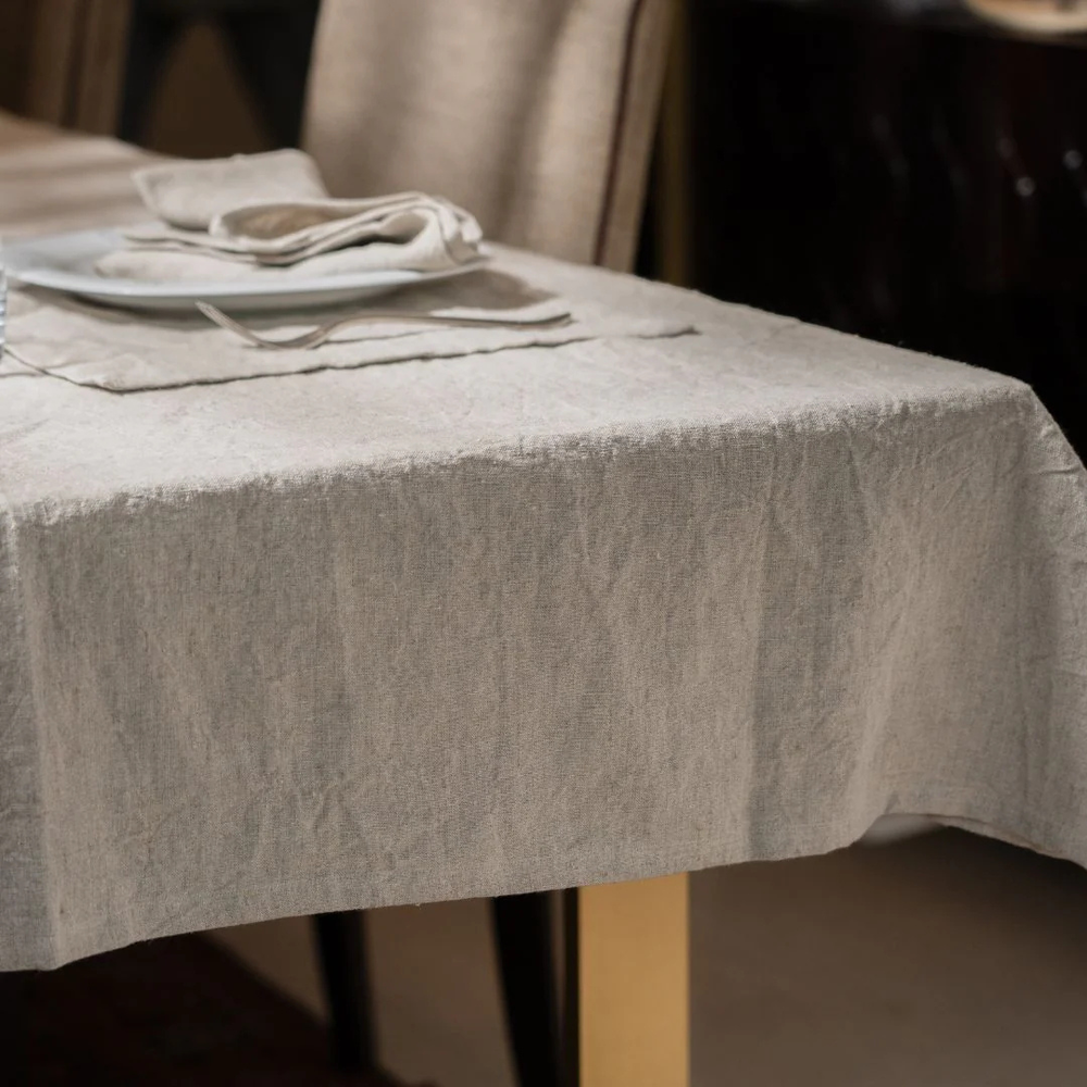 Table with a textured gray tablecloth and white plates with silverware.