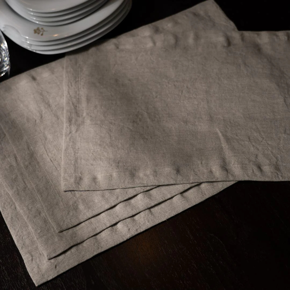 Gray textured placemats on a dark surface with stacked plates in the background.