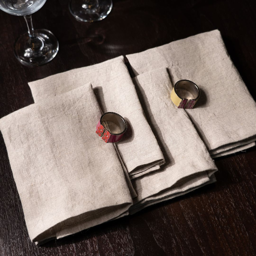 Folded beige napkins with decorative rings on a dark wooden surface