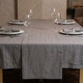 Dining table set with gray tablecloth, plates, glasses, and napkins.