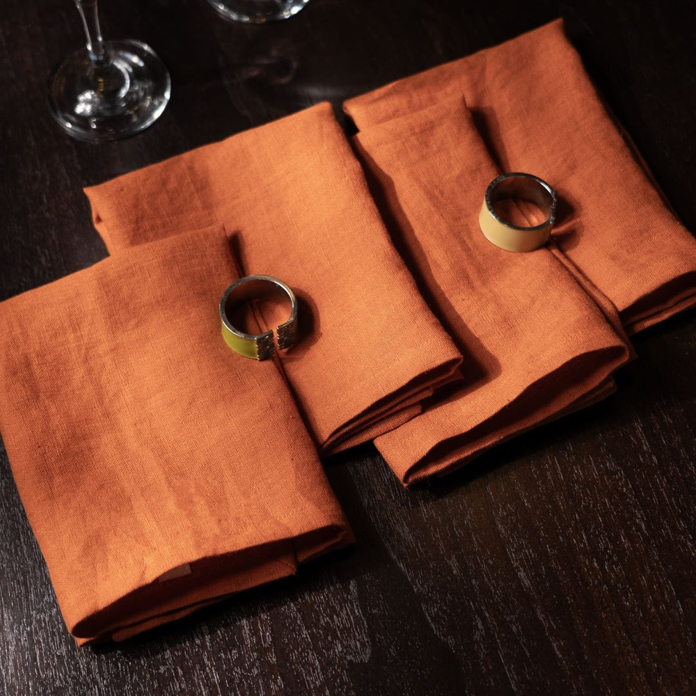 Two brown napkins with rings on a dark surface