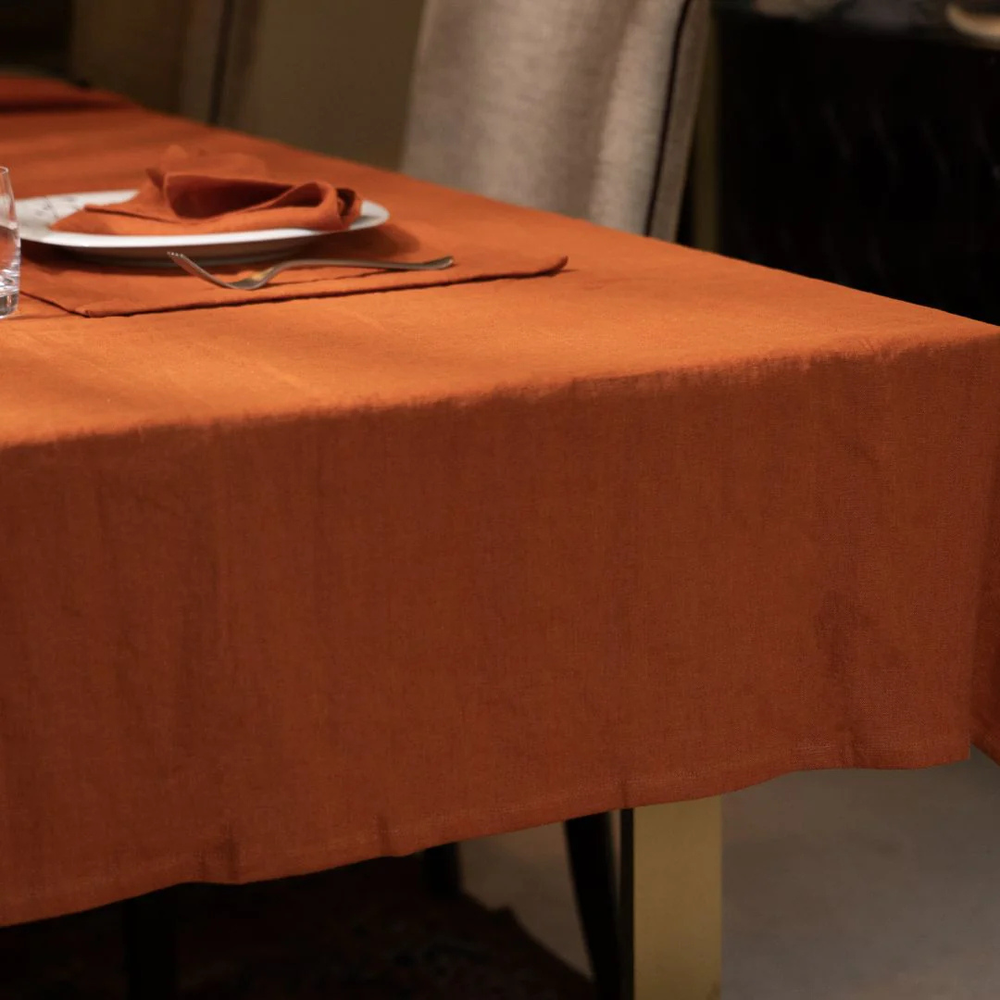 Orange tablecloth on a table with plates and cutlery in a blurred indoor setting
