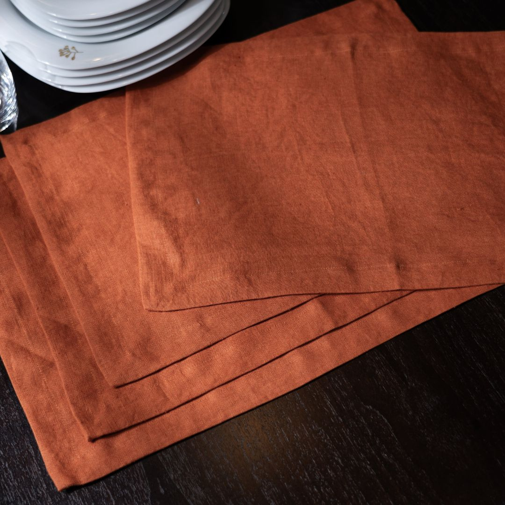 Brown placemats on a dark surface with white plates in the background